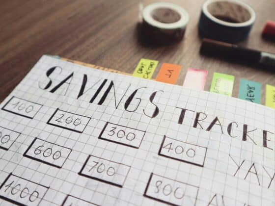 Graph paper with "Savings Tracker" written in pencil at the top and rectangles in rows and columns across the page with savings goals in them.
