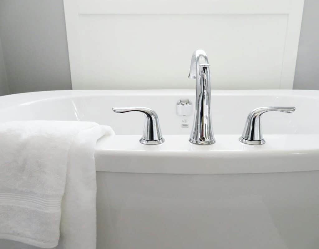 Photo of a bathtub with a white towel draped over the edge featuring a low flow faucet.