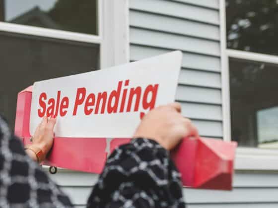 Sale Pending sign in front of a house with grey siding.