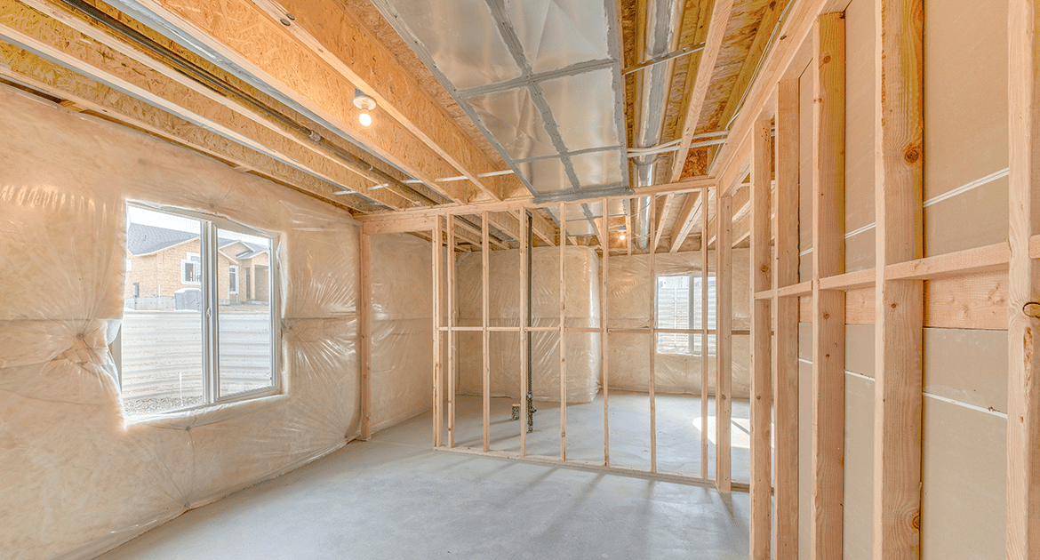 An unfinished basement framed with new wood studs and insulated walls, daylight coming through a window