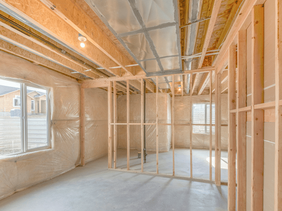 An unfinished basement framed with new wood studs and insulated walls, daylight coming through a window